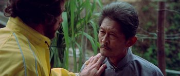 Movie still from “Enter the Dragon” (1973), directed by Robert Clouse – An older man is being examined by an old man; Close Up shot, Over the shoulder angle
