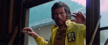 Movie still from “Enter the Dragon” (1973), directed by Robert Clouse – A man in a yellow jacket with blood all over his face; Close Up shot, Low angle