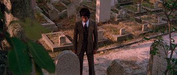 Movie still from “Enter the Dragon” (1973), directed by Robert Clouse – A man in a suit standing in front of a grave; Wide shot, Low angle