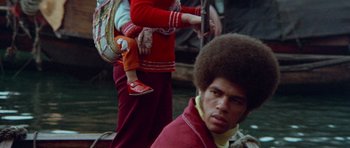 Movie still from “Enter the Dragon” (1973), directed by Robert Clouse – A man and a woman with a baby in a red sweater; Close Up shot, Low angle