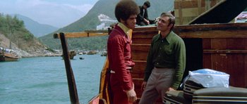 Movie still from “Enter the Dragon” (1973), directed by Robert Clouse – Two men are talking on a boat in the water; Medium shot, Low angle