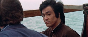 Movie still from “Enter the Dragon” (1973), directed by Robert Clouse – A person sitting in a boat; Close Up shot, Over the shoulder angle