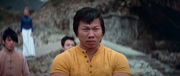 Movie still from “Enter the Dragon” (1973), directed by Robert Clouse – A man in a yellow shirt is looking at the camera; Close Up shot, Low angle