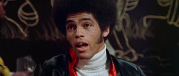 Movie still from “Enter the Dragon” (1973), directed by Robert Clouse – A man with a black afro is wearing a white sweater; Close Up shot, Low angle