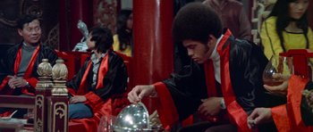Movie still from “Enter the Dragon” (1973), directed by Robert Clouse – A man in a red robe is holding a silver object; Medium shot, Low angle