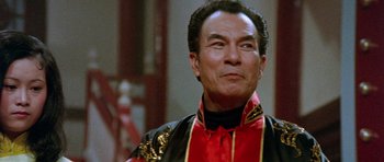 Movie still from “Enter the Dragon” (1973), directed by Robert Clouse – An older man wearing a red and black outfit; Close Up shot, Low angle