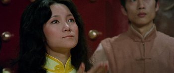 Movie still from “Enter the Dragon” (1973), directed by Robert Clouse – A woman in a yellow and white dress clapping; Close Up shot, Low angle
