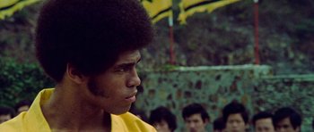 Movie still from “Enter the Dragon” (1973), directed by Robert Clouse – A young man with a yellow shirt is looking to his left; Close Up shot, Low angle
