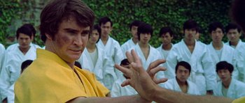 Movie still from “Enter the Dragon” (1973), directed by Robert Clouse – A group of men in white robes and one man in yellow; Close Up shot, Low angle
