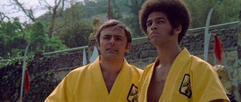 Movie still from “Enter the Dragon” (1973), directed by Robert Clouse – Two men in yellow robes standing next to each other; Close Up shot, Low angle