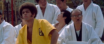 Movie still from “Enter the Dragon” (1973), directed by Robert Clouse – A group of men in white and yellow robes; Medium shot, Over the shoulder angle