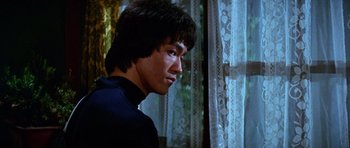 Movie still from “Enter the Dragon” (1973), directed by Robert Clouse – A man standing in front of a window with lace curtains; Close Up shot, Low angle