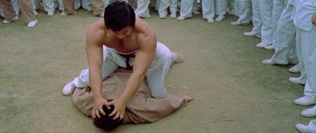 Movie still from “Enter the Dragon” (1973), directed by Robert Clouse – A man in white pants and a black tie kneeling on the ground; Medium shot, High angle