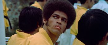 Movie still from “Enter the Dragon” (1973), directed by Robert Clouse – A person wearing a yellow shirt; Close Up shot, Low angle