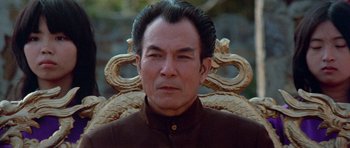 Movie still from “Enter the Dragon” (1973), directed by Robert Clouse – A man sitting in a chair with a snake on his head; Close Up shot, Low angle