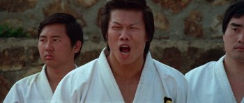 Movie still from “Enter the Dragon” (1973), directed by Robert Clouse – A man in a white robe is yawning with his eyes closed; Close Up shot, Low angle