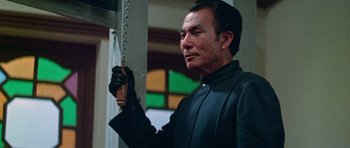 Movie still from “Enter the Dragon” (1973), directed by Robert Clouse – A man in a black leather jacket holding a chain; Medium shot, Low angle