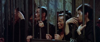 Movie still from “Enter the Dragon” (1973), directed by Robert Clouse – A group of people behind a metal fence; Medium shot, High angle