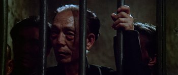 Movie still from “Enter the Dragon” (1973), directed by Robert Clouse – An old man behind a metal fence in a dark room; Close Up shot, Low angle