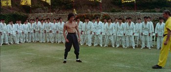 Movie still from “Enter the Dragon” (1973), directed by Robert Clouse – A group of men in white uniforms stand in a field; Wide shot, Low angle