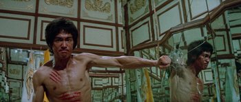 Movie still from “Enter the Dragon” (1973), directed by Robert Clouse – A man is holding a bow and arrow in a room; Medium shot, Low angle