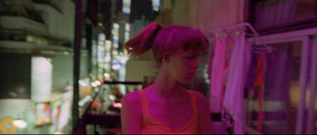 Movie still from “Enter the Void” (2009), directed by Gaspar Noé – A woman with pink hair is standing in a room; Medium shot, High angle