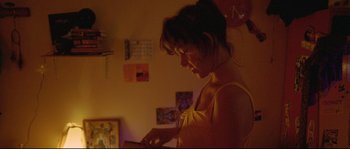Movie still from “Enter the Void” (2009), directed by Gaspar Noé – A woman is looking at her cell phone in the dark; Medium shot, Low angle
