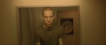 Movie still from “Enter the Void” (2009), directed by Gaspar Noé – A man with a shaved head is standing in front of a bathroom mirror; Close Up shot, Low angle