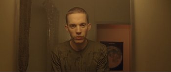 Movie still from “Enter the Void” (2009), directed by Gaspar Noé – A young man with a shaved head is posing for the camera; Close Up shot, Low angle