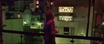 Movie still from “Enter the Void” (2009), directed by Gaspar Noé – A woman standing in front of an exit sign; Wide shot, High angle