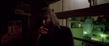 Movie still from “Enter the Void” (2009), directed by Gaspar Noé – A man with long hair is smoking a cigarette; Close Up shot, Low angle