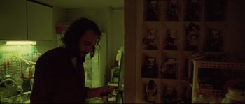 Movie still from “Enter the Void” (2009), directed by Gaspar Noé – A man standing in a room looking at his phone; Medium shot, Low angle