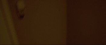 Movie still from “Enter the Void” (2009), directed by Gaspar Noé – A dark brown background with a light on it; Extreme Close Up shot, Low angle