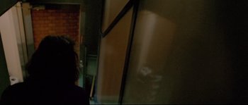 Movie still from “Enter the Void” (2009), directed by Gaspar Noé – A woman standing next to a wall in a dark room; Medium shot, Low angle