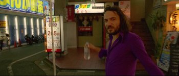 Movie still from “Enter the Void” (2009), directed by Gaspar Noé – A man in a purple shirt holding up a bottle of water; Medium shot, Low angle