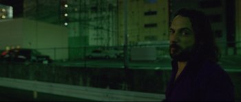 Movie still from “Enter the Void” (2009), directed by Gaspar Noé – A man standing in front of a building at night; Close Up shot, Low angle