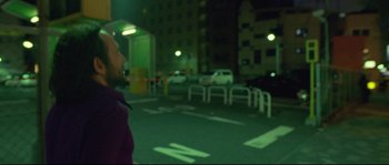 Movie still from “Enter the Void” (2009), directed by Gaspar Noé – A man standing in a parking lot at night; Medium shot, Low angle