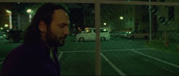 Movie still from “Enter the Void” (2009), directed by Gaspar Noé – A man standing in a parking lot at night looking out a window; Close Up shot, Over the shoulder angle