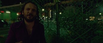 Movie still from “Enter the Void” (2009), directed by Gaspar Noé – A man standing in front of a chain link fence at night; Close Up shot, Low angle