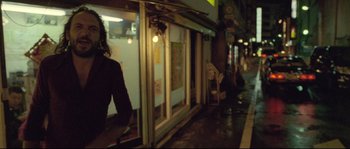 Movie still from “Enter the Void” (2009), directed by Gaspar Noé – A woman walking down a street past a store; Medium shot, Low angle