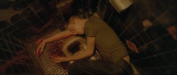 Movie still from “Enter the Void” (2009), directed by Gaspar Noé – A man laying on the floor next to an open toilet; Medium shot, Overhead angle