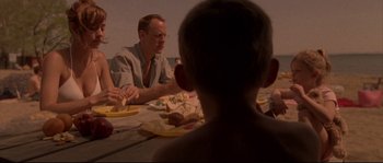 Movie still from “Enter the Void” (2009), directed by Gaspar Noé – A man sitting at a dinner table with a young child; Medium shot, Over the shoulder angle