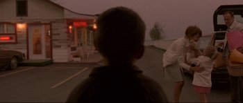 Movie still from “Enter the Void” (2009), directed by Gaspar Noé – A young boy standing on the side of a road; Wide shot, Over the shoulder angle
