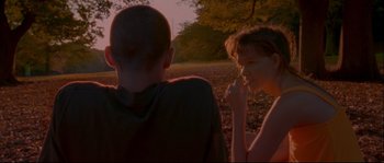 Movie still from “Enter the Void” (2009), directed by Gaspar Noé – A man and a woman sitting in the grass; Medium shot, Over the shoulder angle