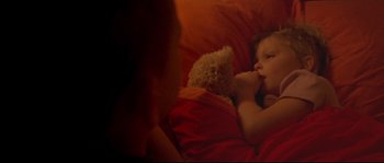 Movie still from “Enter the Void” (2009), directed by Gaspar Noé – A little girl laying in a bed with a teddy bear; Close Up shot, High angle