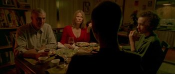 Movie still from “Enter the Void” (2009), directed by Gaspar Noé – A group of people sitting at a dinner table; Medium shot, Over the shoulder angle