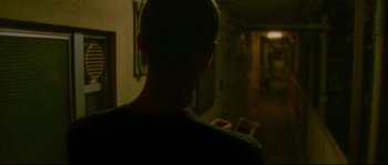 Movie still from “Enter the Void” (2009), directed by Gaspar Noé – A man standing in a dark room looking at his phone; Medium shot, Over the shoulder angle