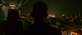 Movie still from “Enter the Void” (2009), directed by Gaspar Noé – A man standing in a car at night with a city in the background; Close Up shot, Low angle