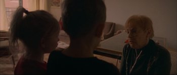 Movie still from “Enter the Void” (2009), directed by Gaspar Noé – A group of people sitting around a table; Medium shot, Over the shoulder angle