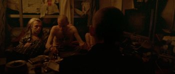 Movie still from “Enter the Void” (2009), directed by Gaspar Noé – A man sitting in front of a mirror in a room; Medium shot, Over the shoulder angle